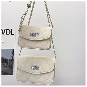 Close-up of quilted cream faux leather bag with silver turn-lock and bead chain