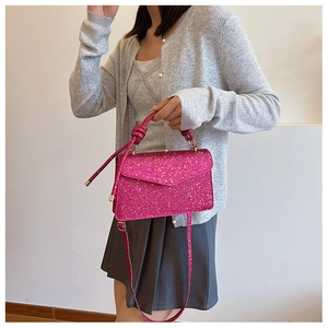 Detail of glitter pink crossbody bag with knotted handle and golden hardware on model