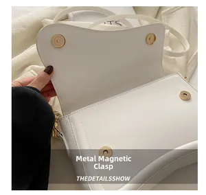 Detail of white leather saddle bag featuring premium golden magnetic snap fasteners