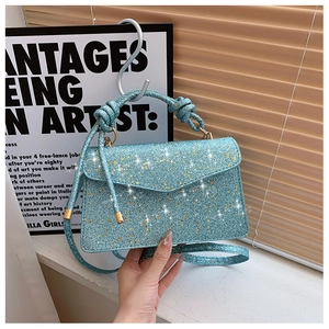 Detail of blue sequin mini bag featuring a woven knot handle and shiny glitter texture
