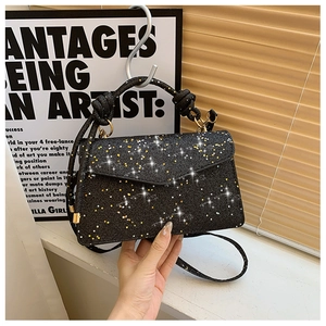Detail of black handbag featuring shimmering gold stars and a knotted handle design