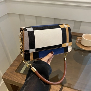 Elegant patchwork checkered shoulder bag with gold chain strap in a modern indoor setting