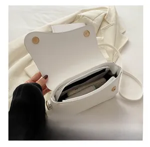 Interior view of white small square bag showing magnetic buckle and zipper pocket space