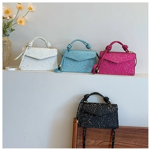 Detail of four glitter handbags in white, blue, pink, and black with knotted handle designs