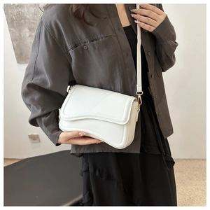 Detailed view of white crossbody bag with wave design flap and gold hardware