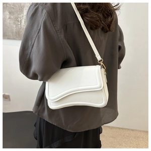 Detail of white leather crossbody bag showing wave-edge flap and fine stitching details