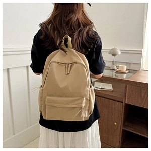 Detail of khaki nylon backpack with double zippers and side pockets on a model