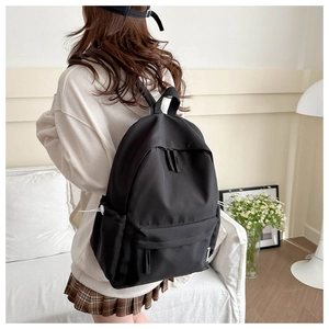 Detail of a large black nylon backpack featuring side pockets shown in a cozy home setting