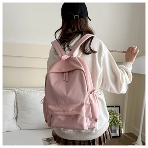 Detailed shot of pink nylon school backpack with drawstring pockets and fashion label