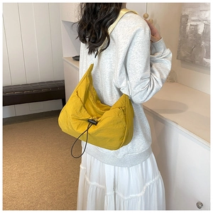 Detail of yellow pleated drawstring crossbody bag showing fabric texture and drape