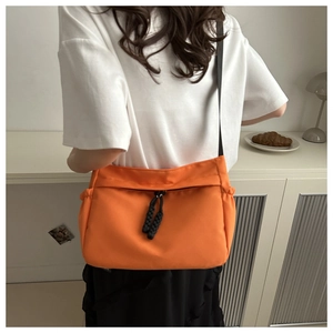 Détail du sac fourre-tout orange en nylon avec cordons de serrage et tirette en corde