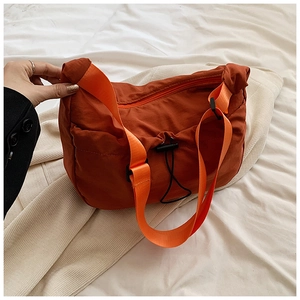 Detail of orange pleated nylon crossbody bag with black drawstring and wide strap