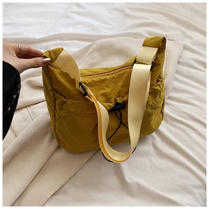 Macro shot of ginger yellow pleated nylon shoulder bag showing durable texture and strap