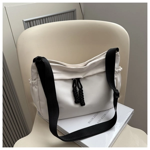 Détail du sac fourre-tout en nylon crème avec zips tissés noirs et poches latérales