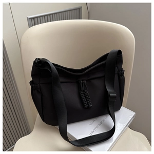 Détail du sac fourre-tout noir en nylon avec bandoulière large et cordons latéraux