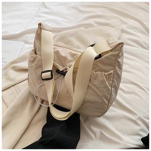 Close-up of pleated beige nylon shoulder bag with woven strap and drawstring detail