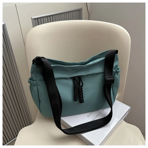 Détail d'un sac cabas en nylon bleu sarcelle avec sangles noires et tirettes tissées
