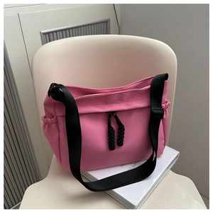 Gros plan du sac fourre-tout en nylon rose avec sangle noire et détails de cordon