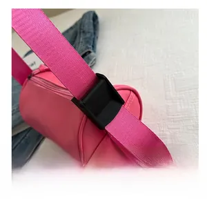 Dettaglio della borsa cilindrica rosa con ampia tracolla e fibbia di regolazione
