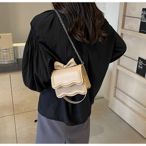 Detail of cream PU leather crossbody bag with bow decoration and scalloped flap edge
