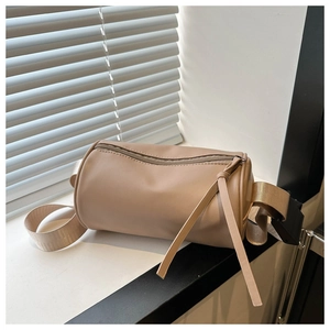 Dettaglio della borsa a tracolla cilindrica minimalista in ecopelle crema con lunghi tiretti