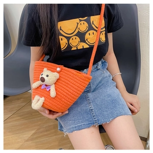 Detail of orange woven mini bag with plush teddy bear and pearl buckle on model