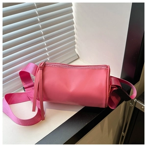Dettaglio della borsa a cilindro rosa con ampia tracolla intrecciata e pelle PU liscia