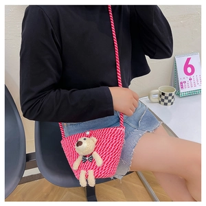 Detail of pink and white woven kid bag with plush bear and pearl closure accessory