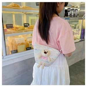 Girl wearing a mini straw crossbody bag with a cute plush bear and colorful stitching