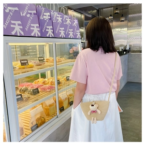 Detail of straw mini crossbody bag with plush bear, pearl clasp and woven strap