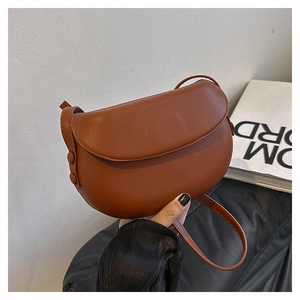 Detailed view of a brown leather saddle bag with smooth flap and adjustable shoulder strap