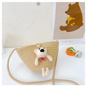 Detail view of mini straw crossbody bag featuring a plush bear and pearl button