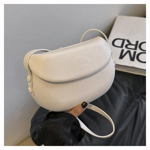 Detail of minimalist white leather saddle bag showing matte texture and side button accent