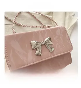 Close-up of pink marble pattern crossbody bag with silver metal bow and chain strap