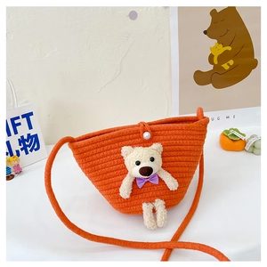 Detail of orange woven mini bag with plush bear charm and pearl button closure