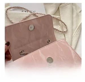 Close-up of the silver magnetic buckle and pleated pink patent leather of the bag