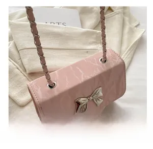 Detail of pink marble pattern handbag featuring a silver metal bow and chain strap