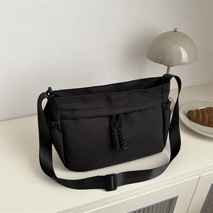 Grand sac fourre-tout en nylon noir avec bandoulière réglable dans un décor minimaliste