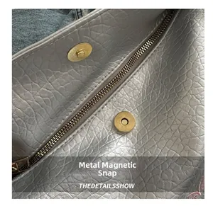 Detail of silver leather bag with golden magnetic buckle and metal zipper closure