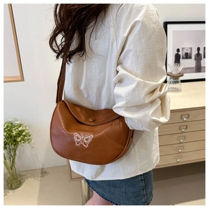 Close-up of caramel leather crossbody bag with white butterfly embroidery and half-moon shape