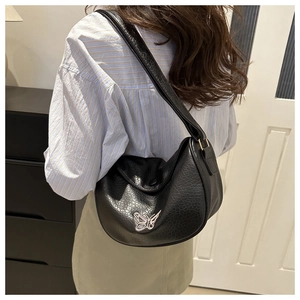 Detail of black pebbled leather dumpling bag featuring white butterfly embroidery