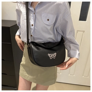 Dettaglio di una borsa a tracolla a mezzaluna in pelle nera con ricamo a farfalla elegante