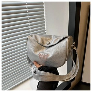 Detail of silver half-moon shoulder bag with pink butterfly and textured finish
