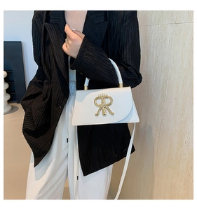 Détail d'un sac bandoulière en cuir blanc avec logo doré élégant et poignée pour femme