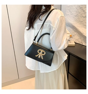 Detail of black crossbody bag featuring a golden R logo and adjustable shoulder strap