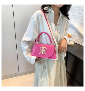 Fashionable rose pink crossbody bag featuring gold metal logo and round top handle