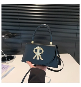 Gros plan d'un sac à main en cuir noir avec un détail de logo couronne en métal doré