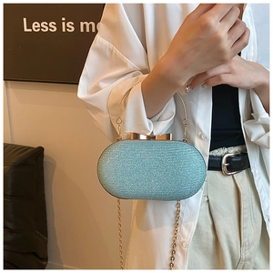 Close-up of light blue glitter evening bag with gold bow clasp and metal handle