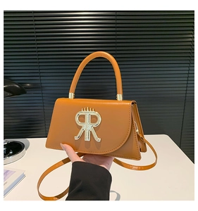Détail du sac trapèze en cuir marron avec logo R doré et poignée ronde