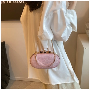 Detailed shot of pink glitter evening clutch with black bow clasp worn with white shirt